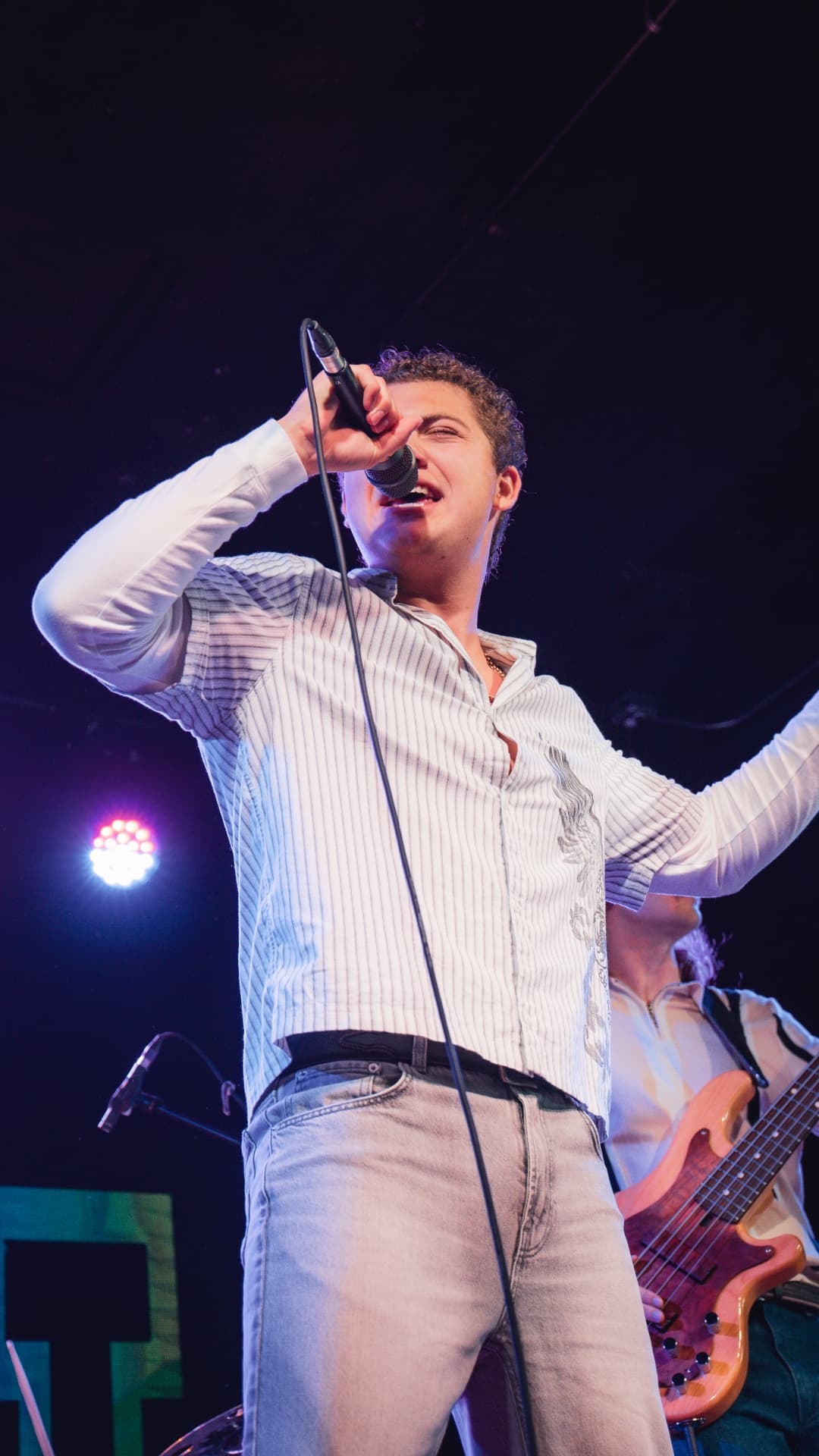 Davey J singing into the mic mid-performance under stage lights