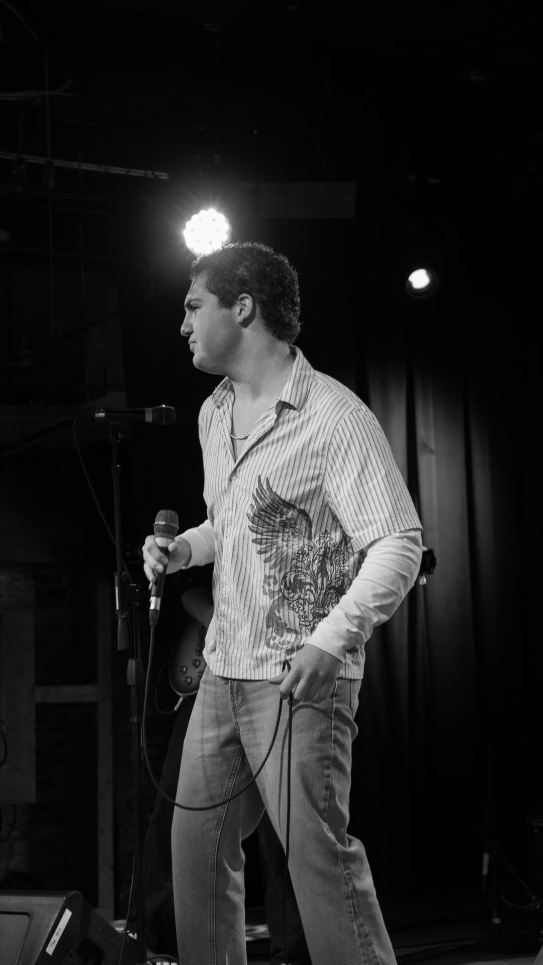 Black and white photo of Davey J on stage holding a microphone